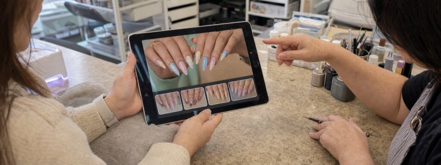 Client showing her chosen design to the nail tech on a tablet